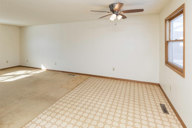 carpeted spare room with baseboards, visible vents, and ceiling fan