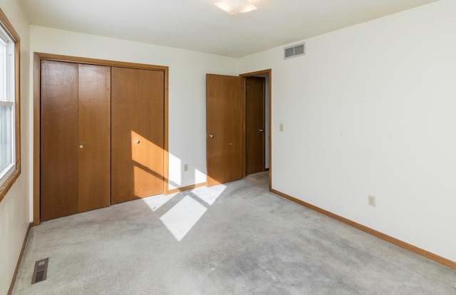 unfurnished bedroom featuring light carpet, visible vents, and a closet