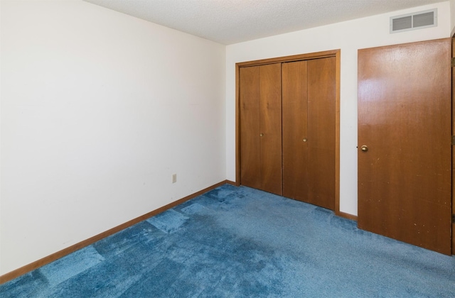 unfurnished bedroom with carpet, visible vents, a textured ceiling, and baseboards