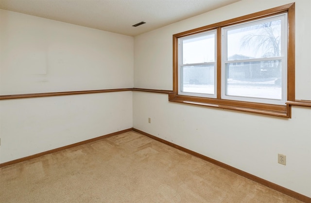 spare room featuring visible vents, baseboards, and light colored carpet