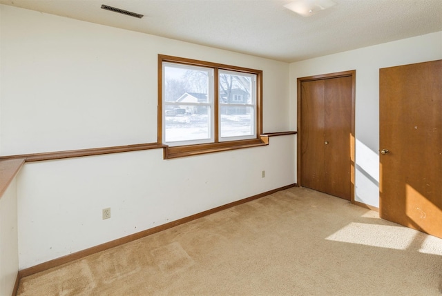 unfurnished bedroom featuring light carpet, two closets, visible vents, and baseboards