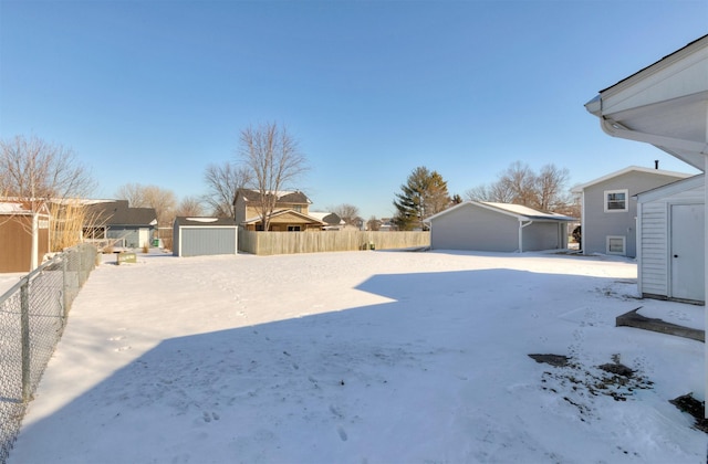 yard layered in snow featuring a residential view, an outdoor structure, fence, and a shed