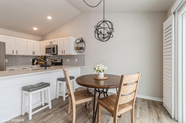 kitchen with stainless steel appliances, light countertops, white cabinetry, pendant lighting, and backsplash