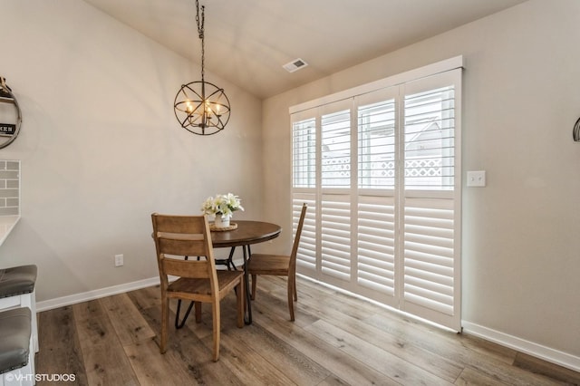 dining space with visible vents, vaulted ceiling, baseboards, and wood finished floors