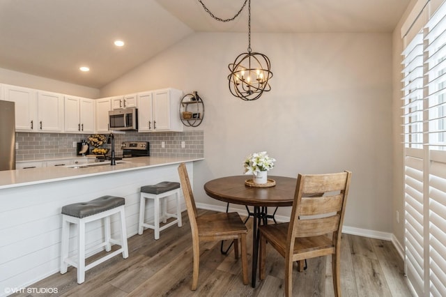 kitchen with white cabinets, stainless steel appliances, light countertops, and decorative light fixtures