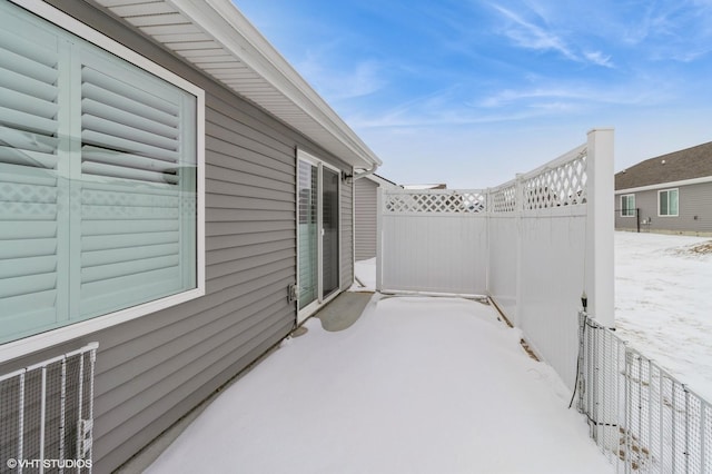 snow covered patio with a garage and fence