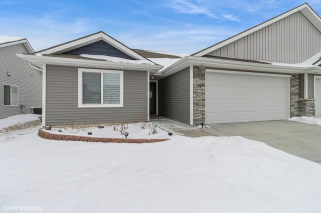 single story home featuring a garage, stone siding, and central air condition unit