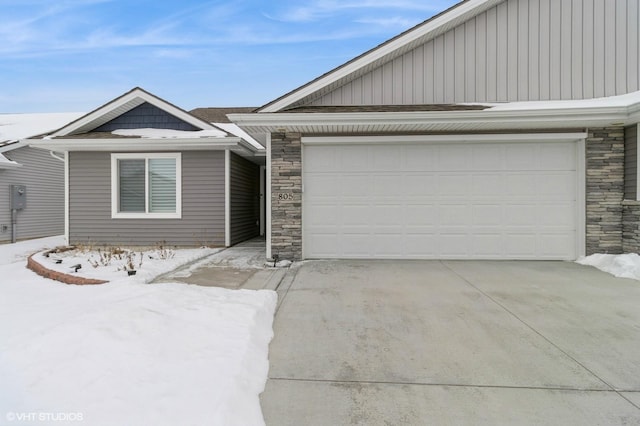 single story home with an attached garage, stone siding, and concrete driveway