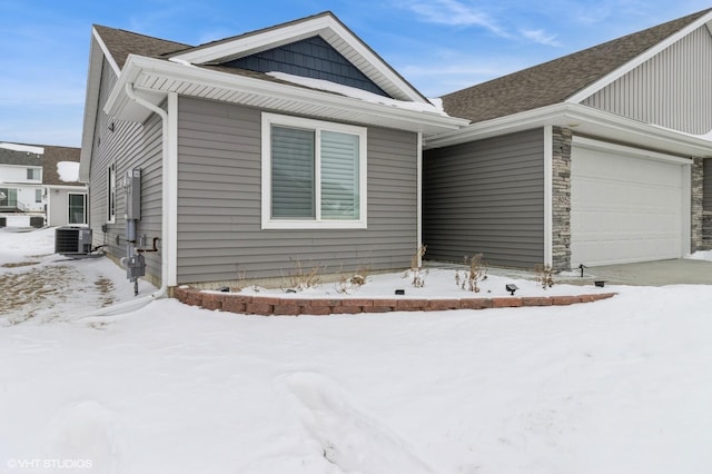 view of front facade with a garage, stone siding, and cooling unit