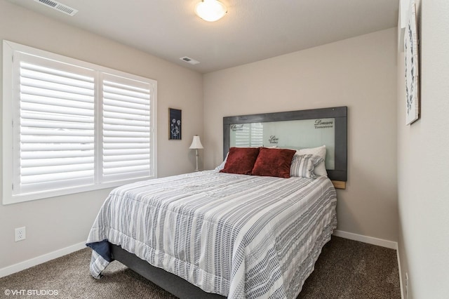 bedroom with baseboards, visible vents, and dark carpet