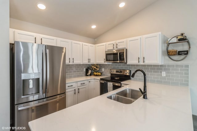 kitchen featuring appliances with stainless steel finishes, lofted ceiling, white cabinetry, and a sink