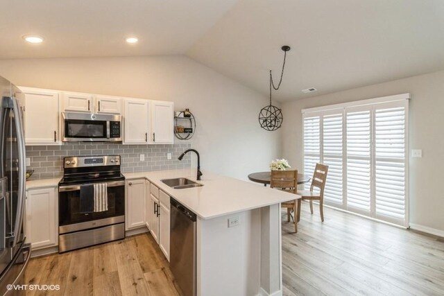 805 Cherry St NW, Bondurant, IA 50035 - kitchen with vaulted ceiling, stainless steel appliances, a sink, light wood-style floors, and a peninsula