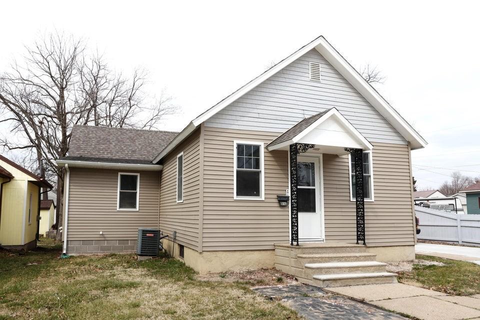 bungalow featuring a front lawn, roof with shingles, and cooling unit