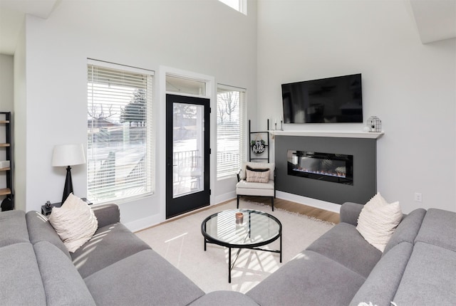 living room with light wood-type flooring, baseboards, and a glass covered fireplace