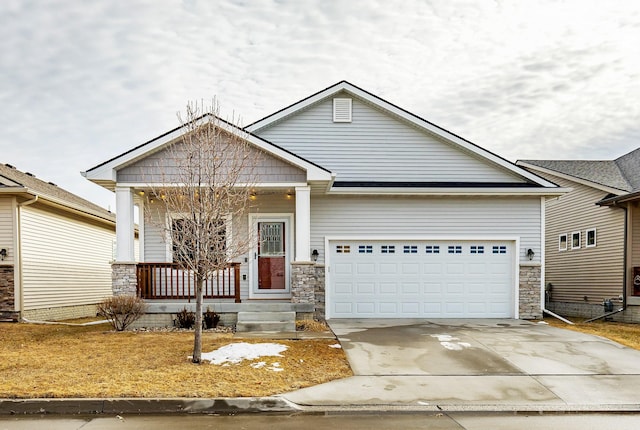 view of front of home featuring a garage, concrete driveway, a porch, and stone siding