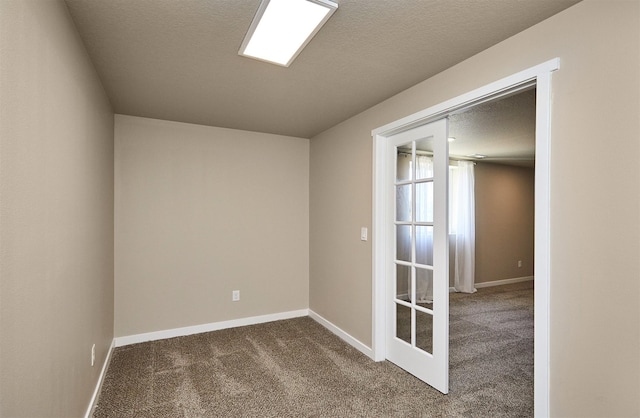 carpeted empty room featuring a textured ceiling and baseboards