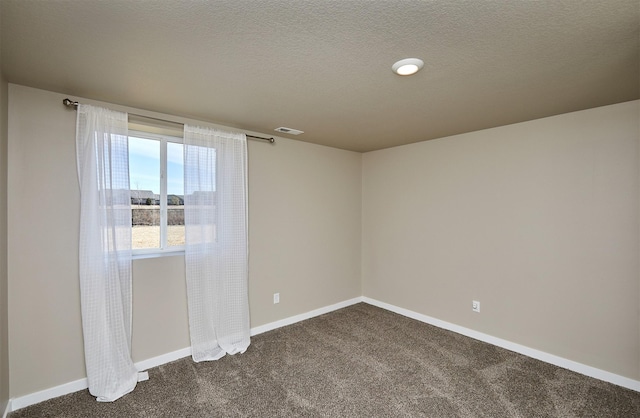 empty room featuring baseboards, visible vents, and dark colored carpet