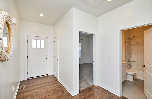 foyer entrance with baseboards, visible vents, dark wood-type flooring, and recessed lighting