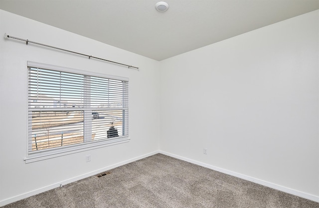 empty room with baseboards, visible vents, and light colored carpet