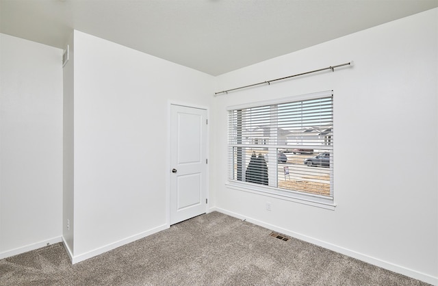 carpeted spare room featuring visible vents and baseboards