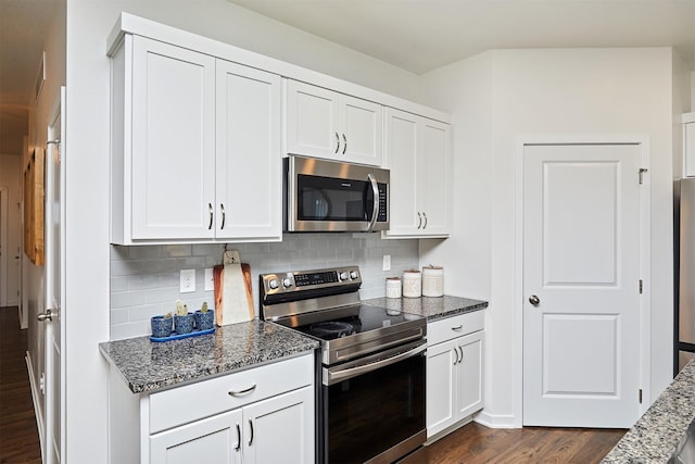 kitchen with stainless steel appliances, dark wood-style floors, white cabinetry, backsplash, and dark stone counters