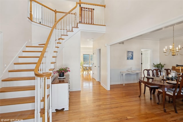 interior space with a towering ceiling, baseboards, a chandelier, and wood finished floors