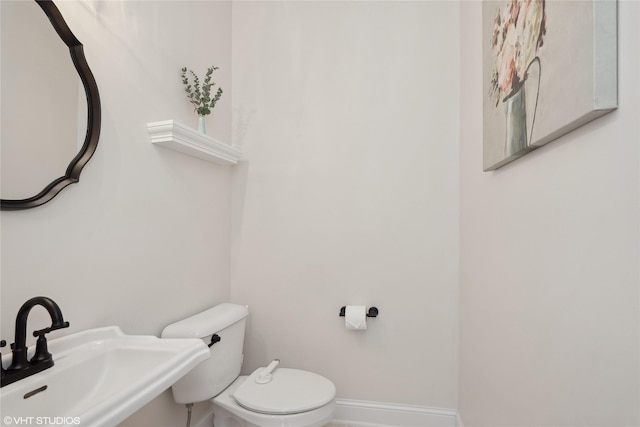 bathroom with baseboards, a sink, and toilet