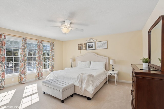 bedroom with a textured ceiling, baseboards, a ceiling fan, and light colored carpet