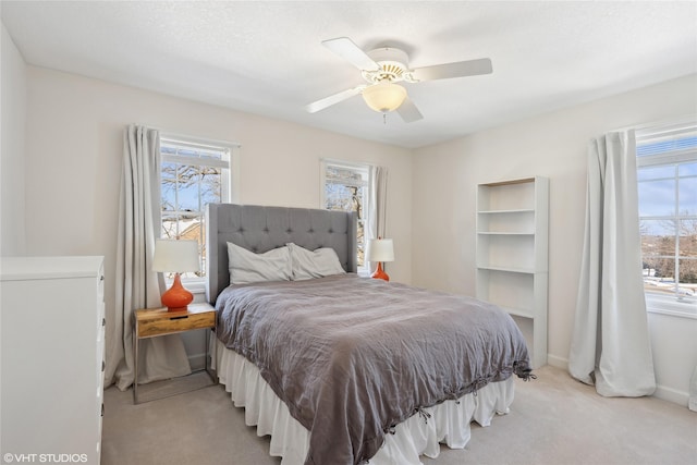 bedroom featuring ceiling fan, multiple windows, and light colored carpet