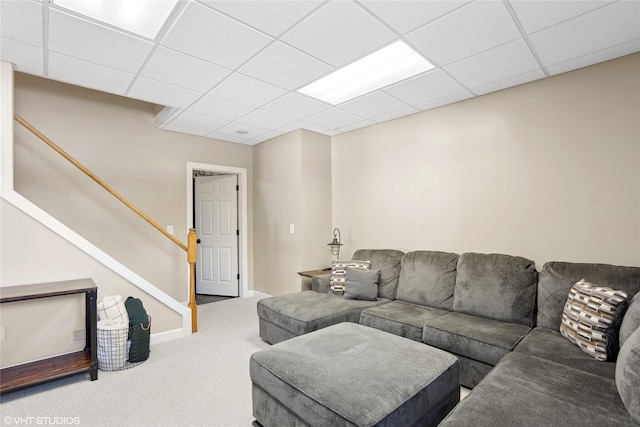 living area with carpet floors, a drop ceiling, stairway, and baseboards