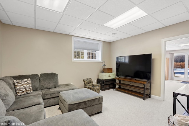 living room featuring light carpet, a healthy amount of sunlight, and a drop ceiling