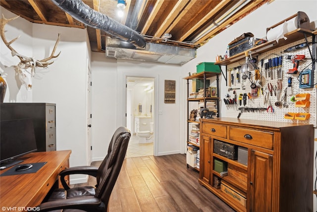 office space with wood finished floors, visible vents, and a workshop area