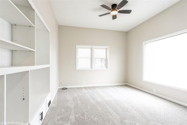 carpeted empty room featuring a textured ceiling, a ceiling fan, and baseboards