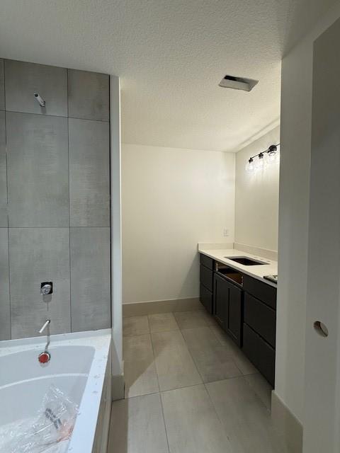 570 El Dorado Ct, Waukee, IA 50263 - bathroom featuring a bathtub, vanity, tile patterned floors, and a textured ceiling