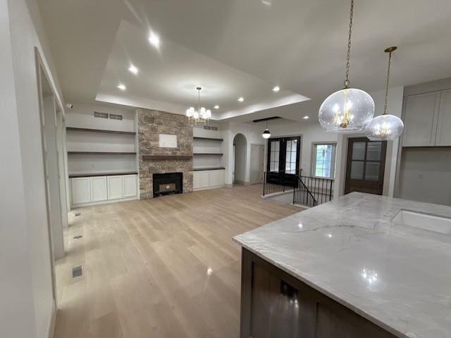 570 El Dorado Ct, Waukee, IA 50263 - kitchen with a chandelier, arched walkways, a tray ceiling, recessed lighting, and light wood-style flooring