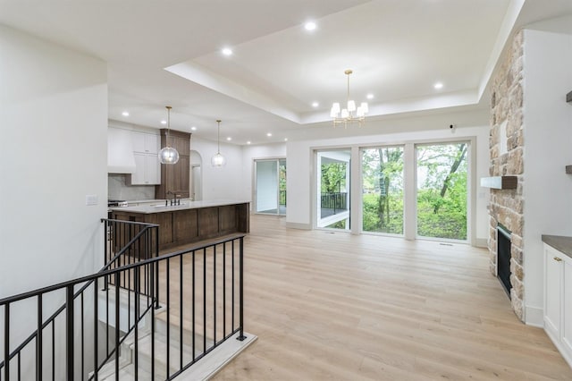 570 El Dorado Ct, Waukee, IA 50263 - kitchen featuring recessed lighting, light wood-style flooring, a chandelier, a stone fireplace, and white cabinets