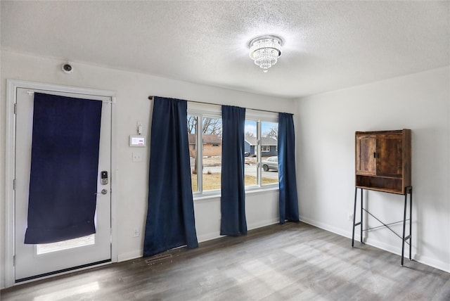 interior space with a textured ceiling, wood finished floors, visible vents, and baseboards