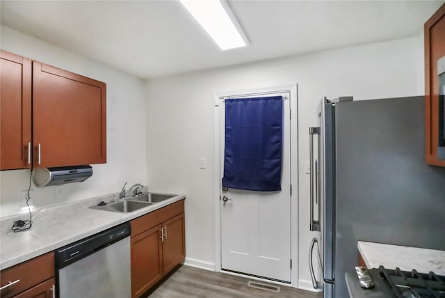 kitchen with visible vents, brown cabinets, stainless steel appliances, light countertops, and a sink