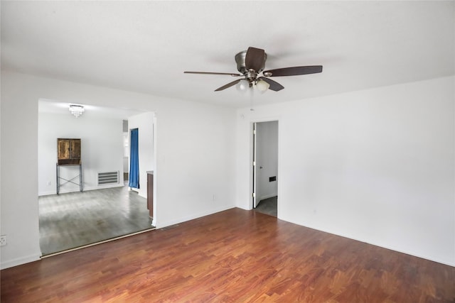 empty room featuring visible vents, ceiling fan, and wood finished floors