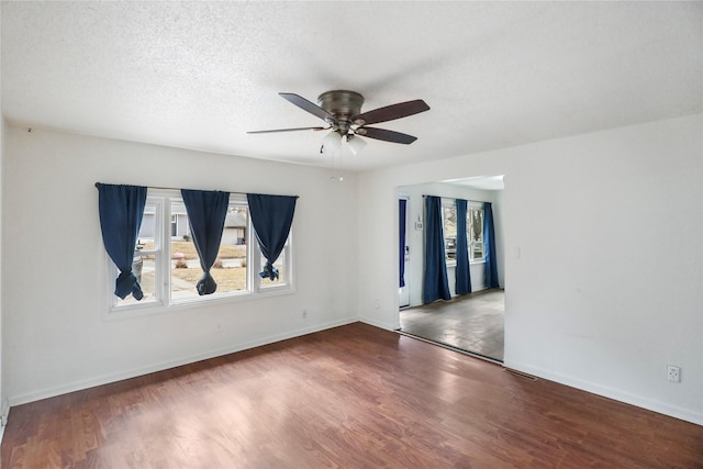 unfurnished room with a wealth of natural light, dark wood finished floors, and a textured ceiling