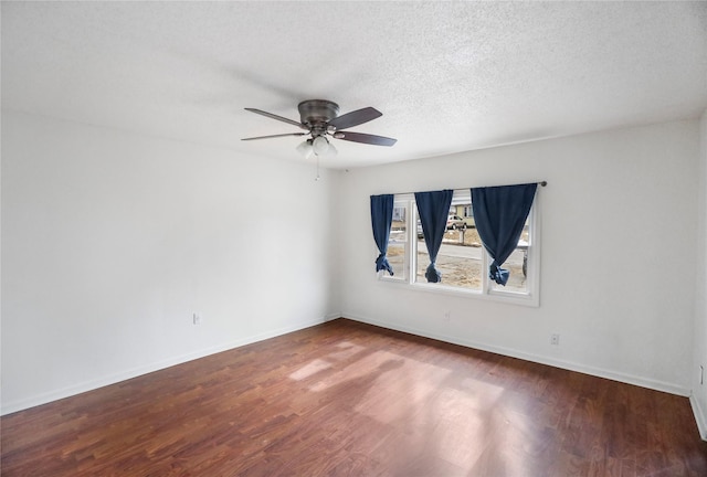 empty room with ceiling fan, a textured ceiling, baseboards, and wood finished floors