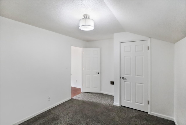 unfurnished bedroom with lofted ceiling, baseboards, dark colored carpet, and a textured ceiling