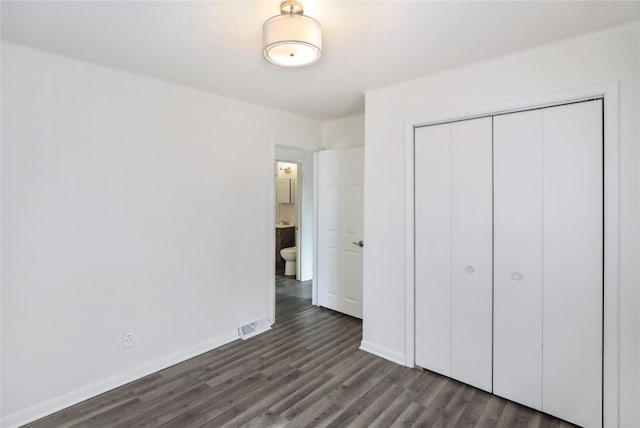 unfurnished bedroom featuring dark wood-type flooring, a closet, visible vents, and baseboards