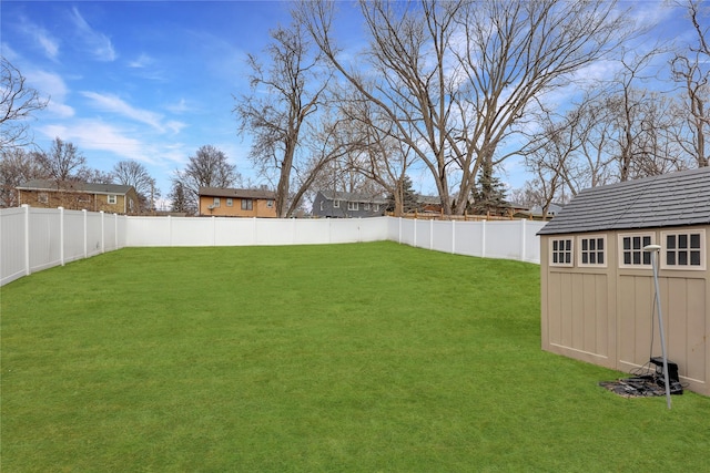 view of yard featuring a fenced backyard, a storage unit, and an outbuilding