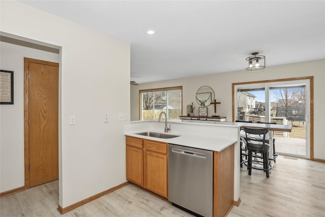 kitchen featuring a healthy amount of sunlight, light countertops, dishwasher, and a sink