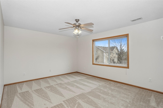 spare room with light carpet, baseboards, visible vents, and a ceiling fan