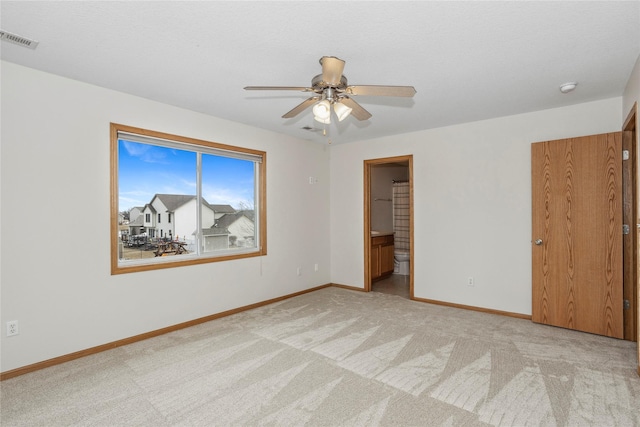 unfurnished bedroom featuring visible vents, light carpet, ceiling fan, ensuite bath, and baseboards