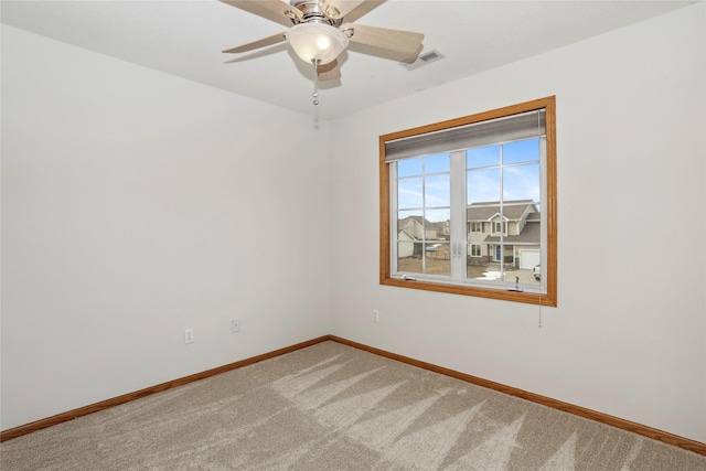 carpeted spare room with a ceiling fan, visible vents, and baseboards