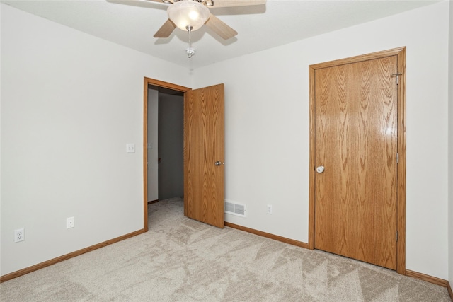 unfurnished bedroom with baseboards, visible vents, light colored carpet, ceiling fan, and a closet