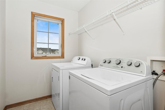 washroom with washer and dryer, laundry area, light tile patterned flooring, and baseboards